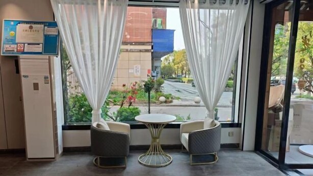 An indoor seating area with two chairs and a small table, a window with curtains, and a sign on the wall.