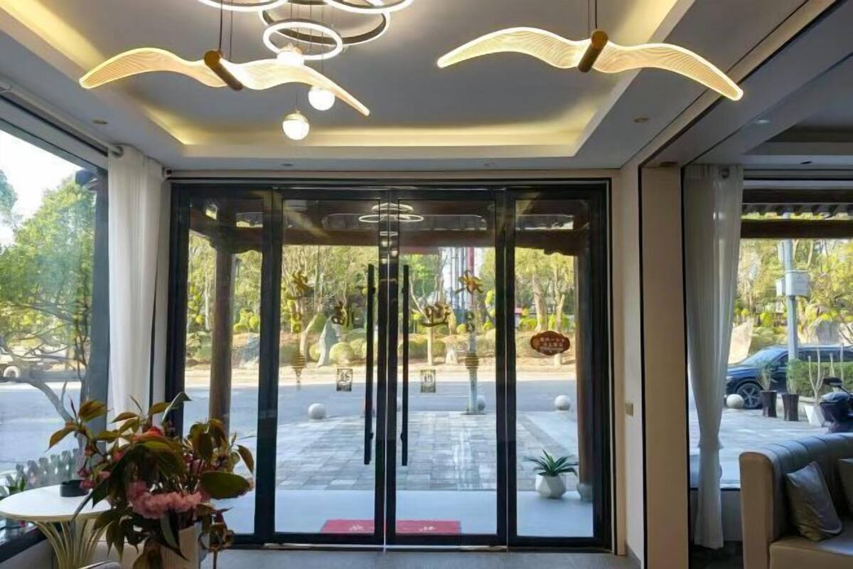 Ein Hotel Eingang mit Glastür, einer Deckenleuchte und Blick ins Freie.