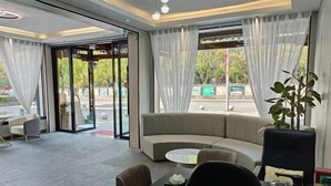 A modern hotel lobby with a curved sofa, a small round table, and a coffee machine.