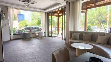 Habitación de hotel con zona de comedor, sofá y vistas al exterior.