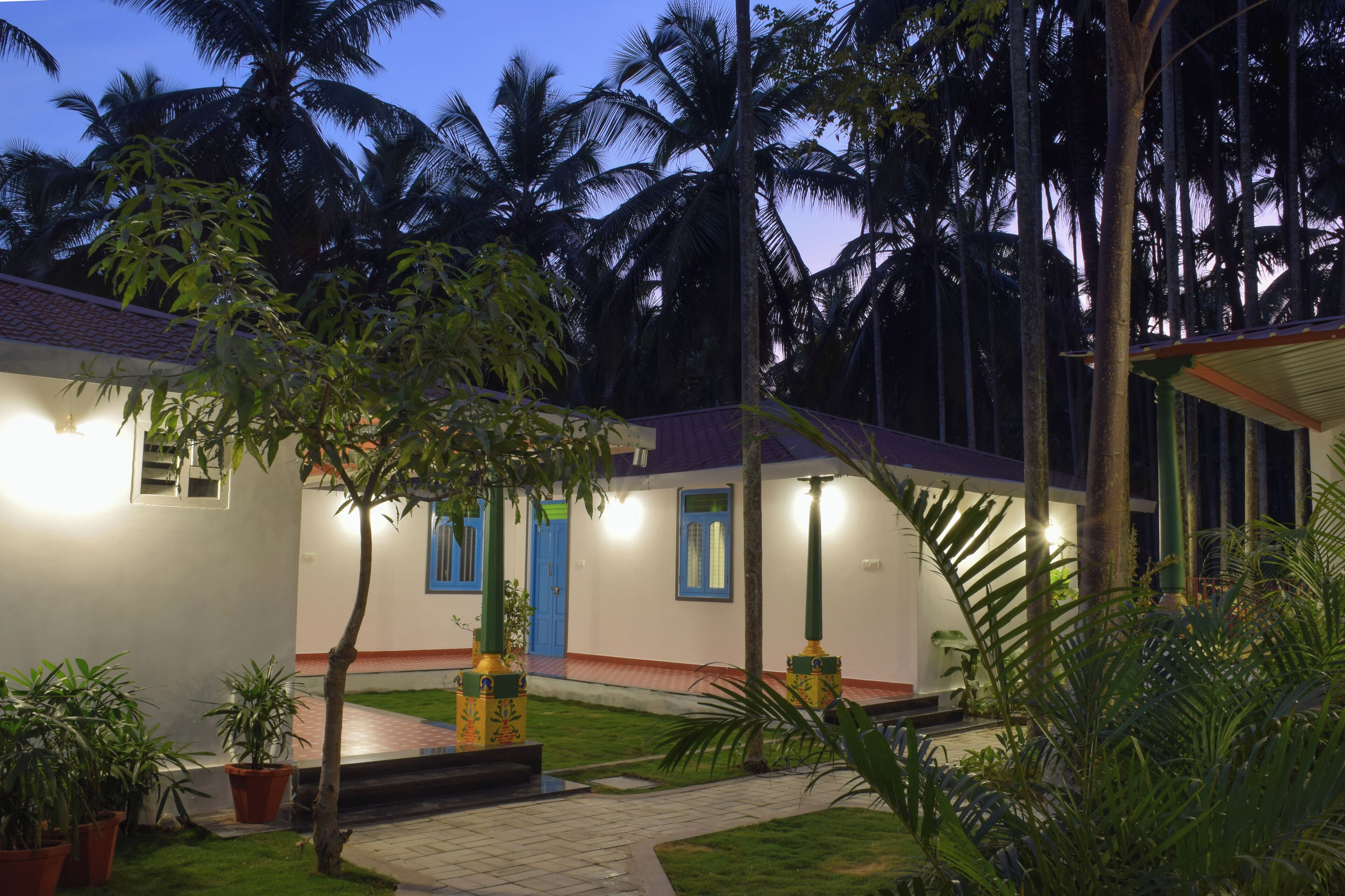 A courtyard with a white building, blue doors, and potted plants.