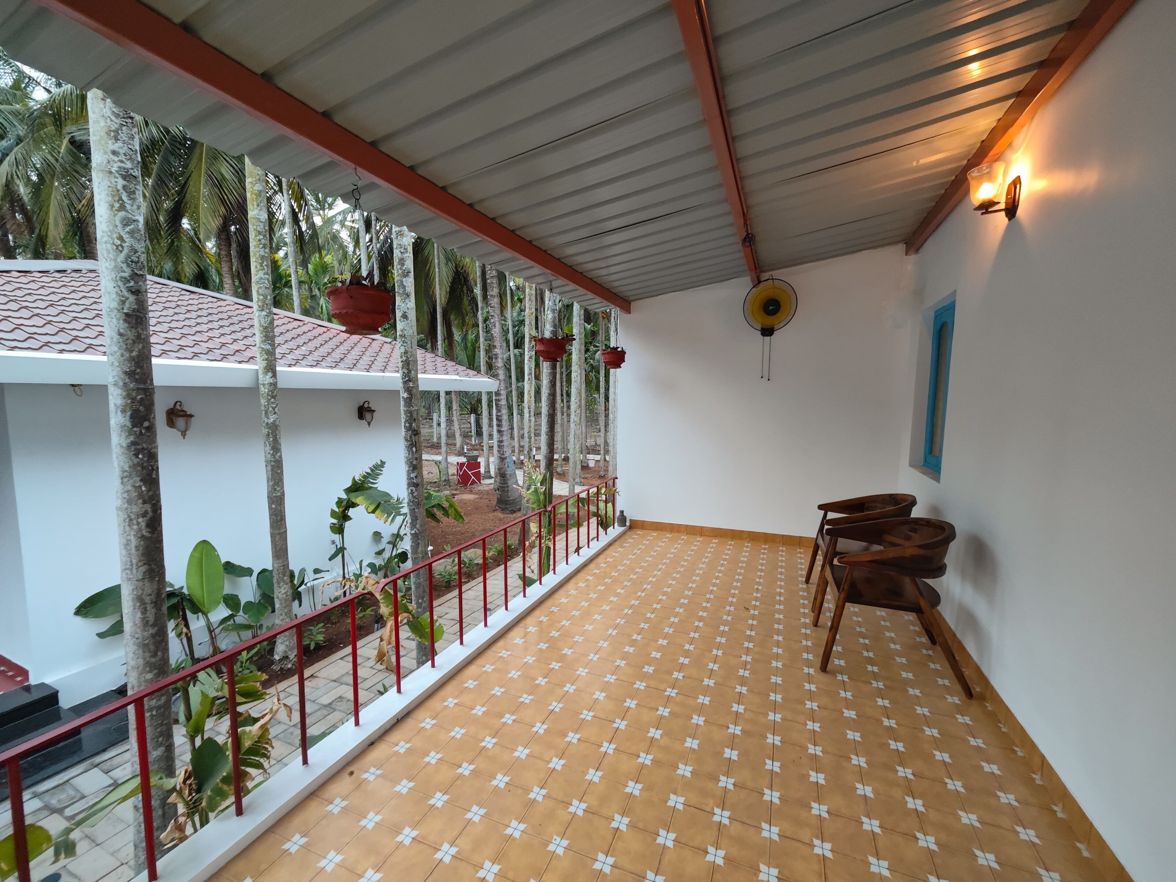 Una habitación con suelo de baldosas, barandilla roja y vistas a palmeras.