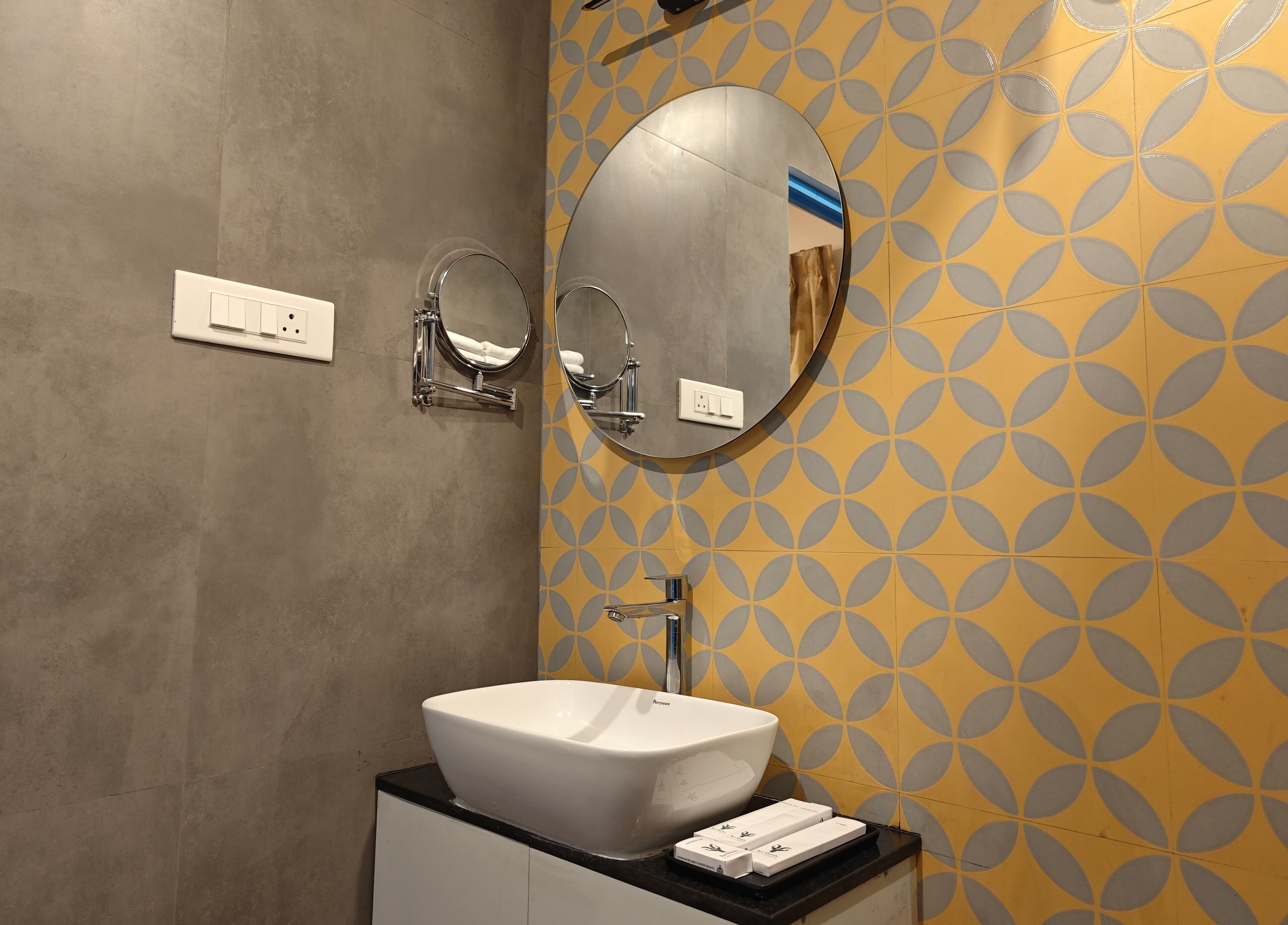 Un baño con un lavamanos blanco, un espejo y un pared con diseño.