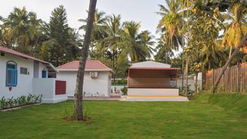A white building with a red roof and blue doors, surrounded by a well-maintained lawn and palm trees.