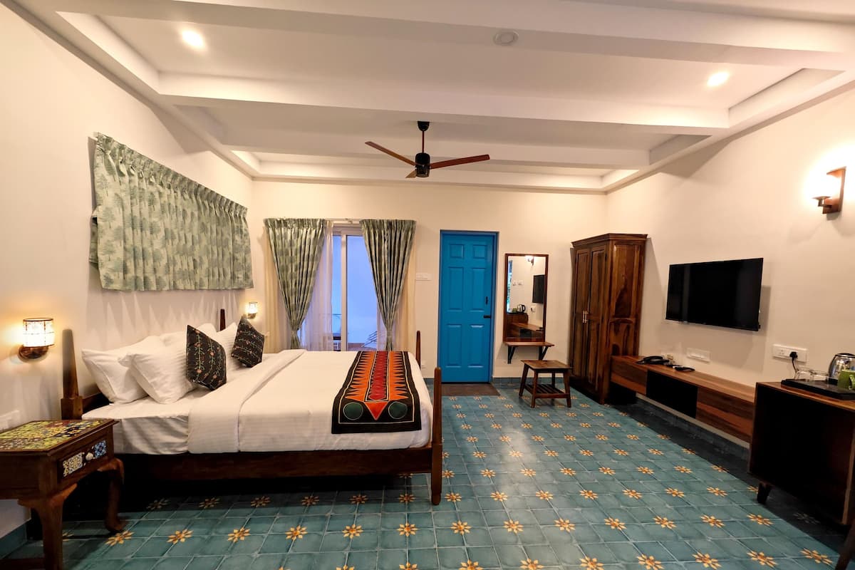 A hotel room with a bed, a desk, a wardrobe, a television, and a ceiling fan.