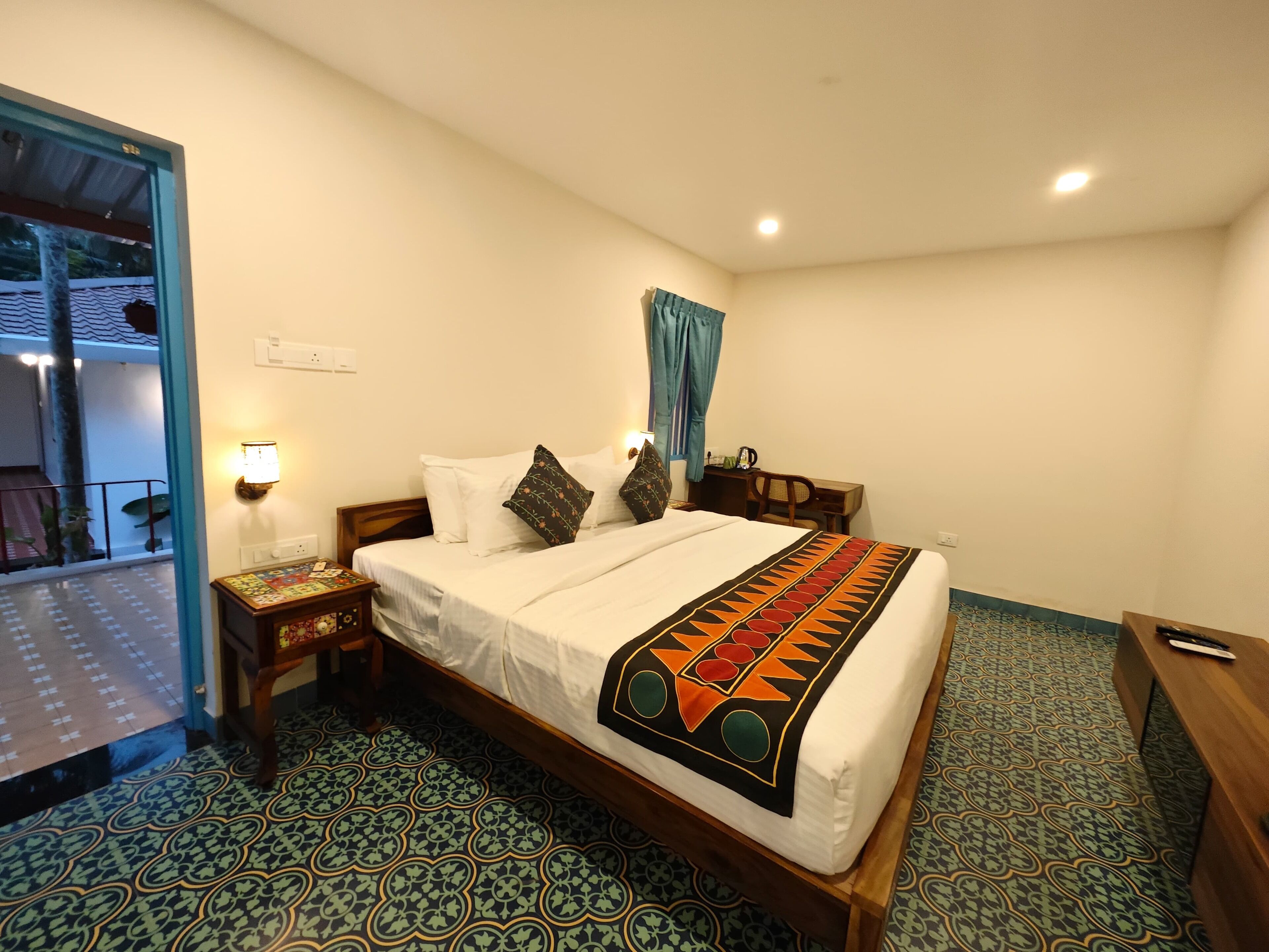 A hotel room with a bed, a nightstand, a desk, and a view of a balcony.