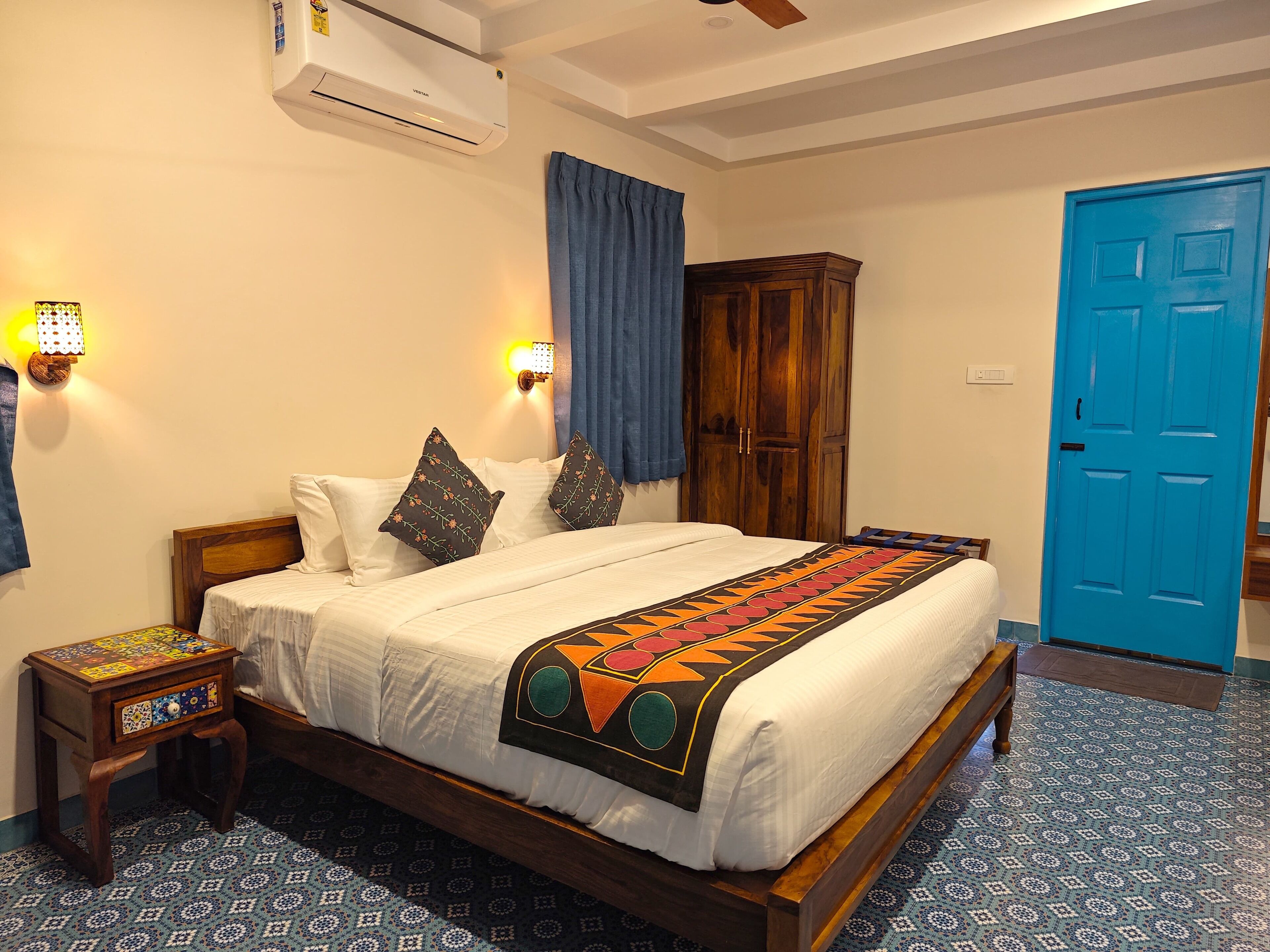 A bedroom with a bed, a nightstand, a wardrobe, and a blue door.