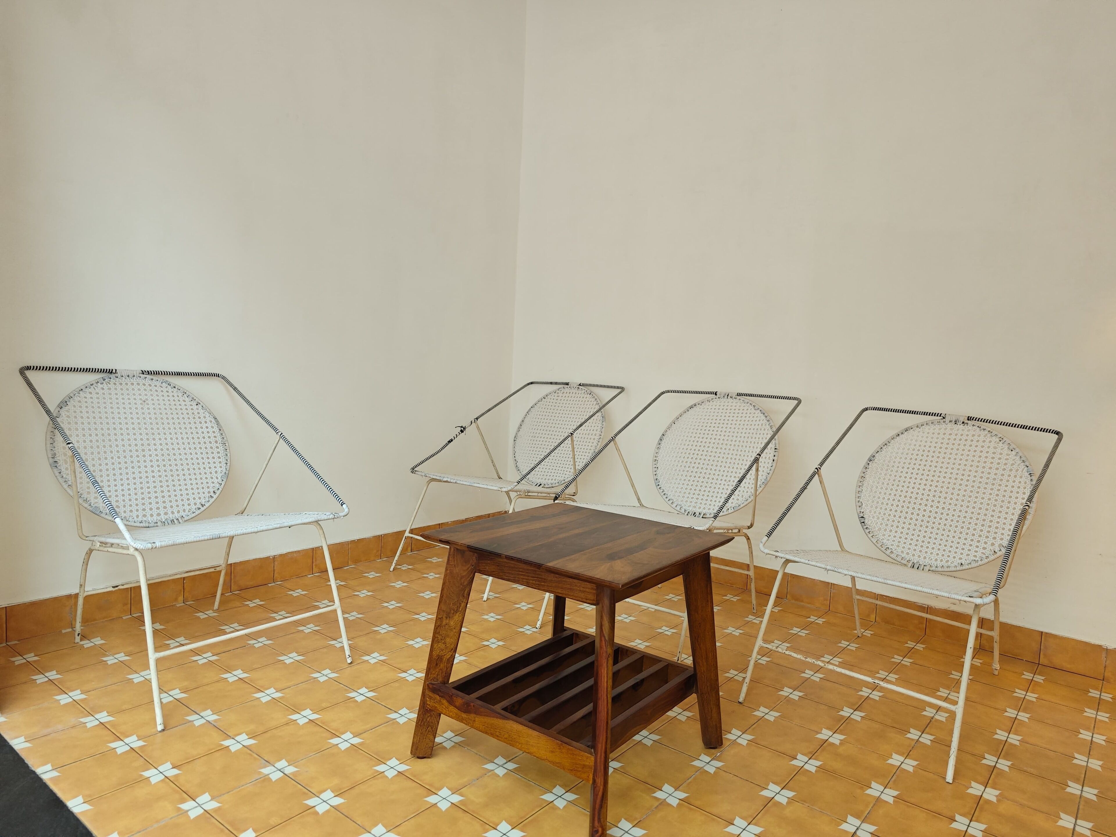 A small room with a wooden table and four metal chairs with mesh backs.