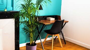 Une pièce avec un bureau en bois, une chaise noire, une plante en pot et un mur de couleur turquoise.
