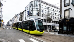 En moderne sporvogn kører på en gade i byen, med bygninger langs begge sider.