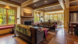 A spacious living room with a fireplace, large windows, and a dining area. - Charming VT ski retreat with hot tub, pool, fire pit & endless mountain views (Weston)