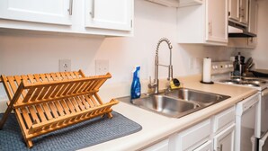 A kitchen with white cabinets, a stainless steel sink, and a wooden drying rack. - Upscale 2 Queen Beds/2 Bath in Charlotte University Area (Charlotte)