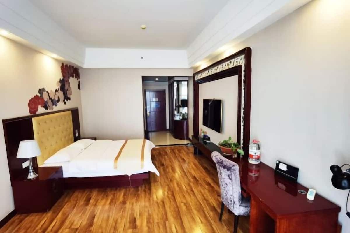 Une chambre d’hôtel comprenant un lit, une table de chevet, une chaise, un bureau et un grand miroir.