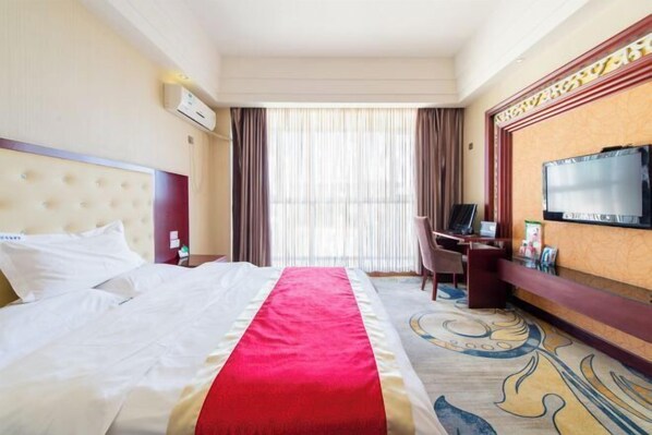 A hotel room with a bed, a desk, a television, and a large window with curtains. - Dingyuan Hotel (Shizuishan)