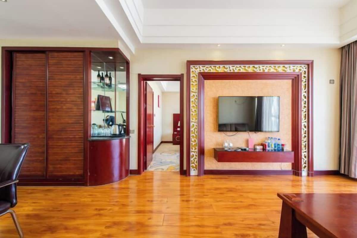 Une chambre d’hôtel avec un plancher en bois, un téléviseur fixé au mur, une armoire en bois et une porte coulissante.