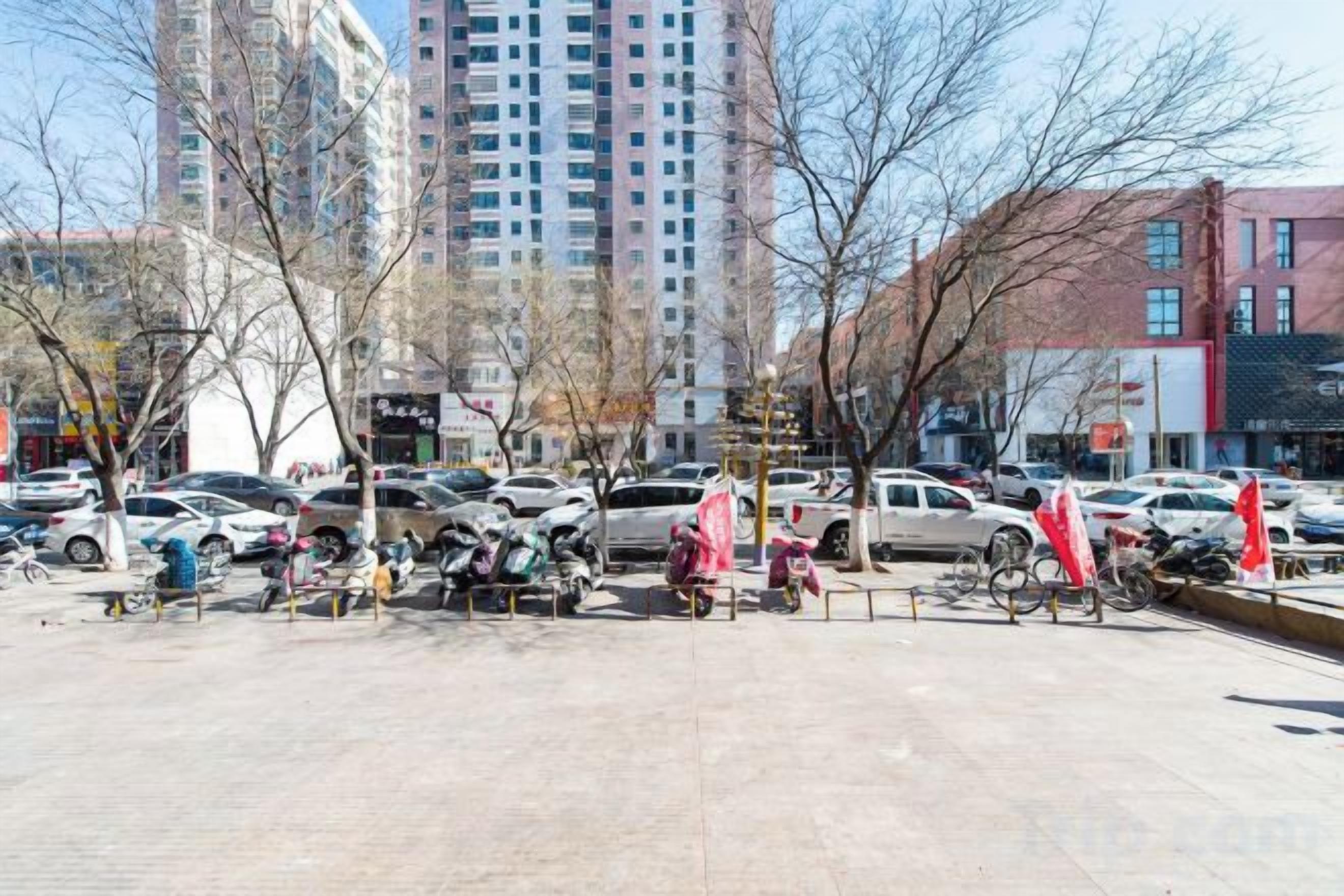 A parking lot with cars and bicycles, surrounded by buildings.
