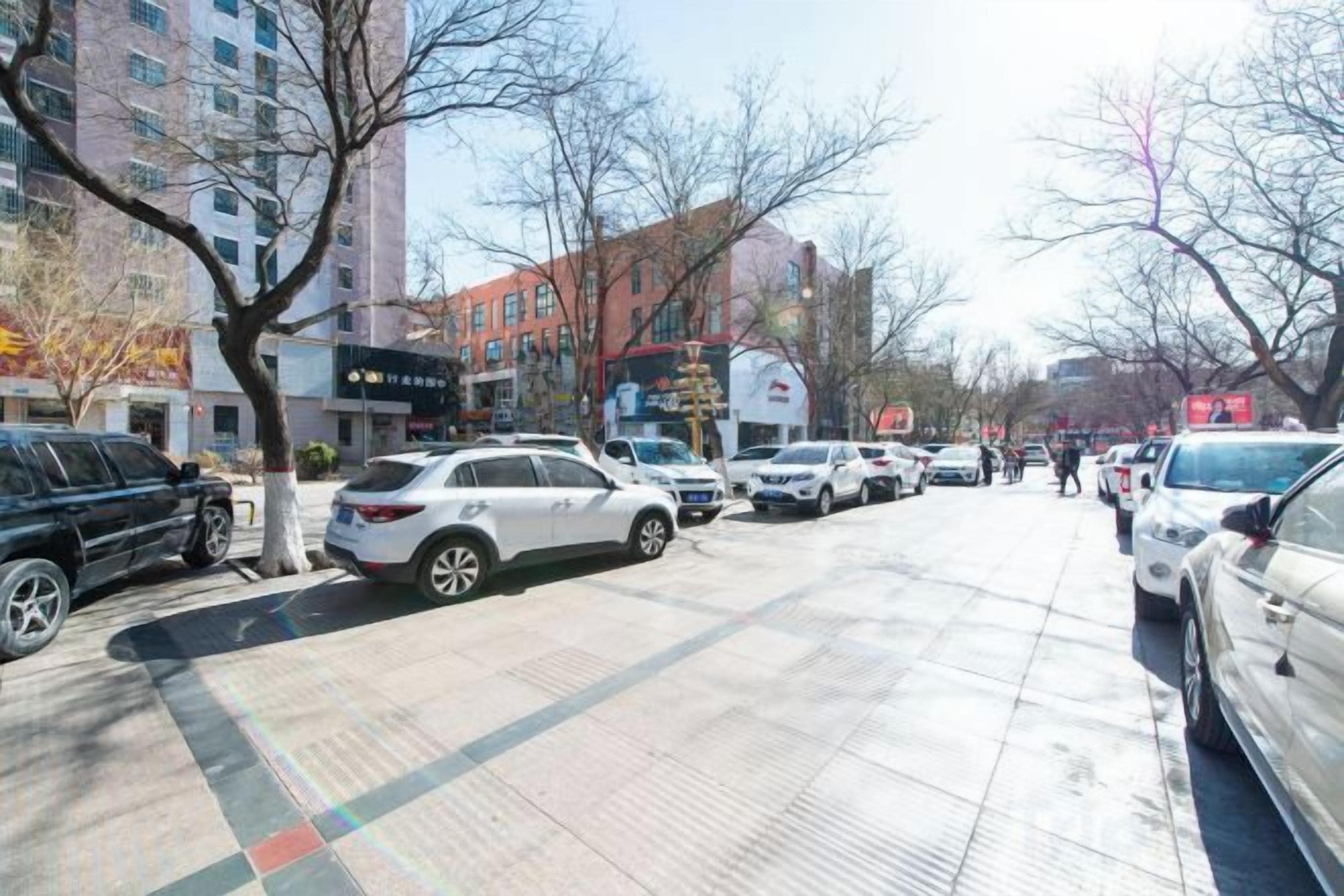 A city street with parked cars and buildings.