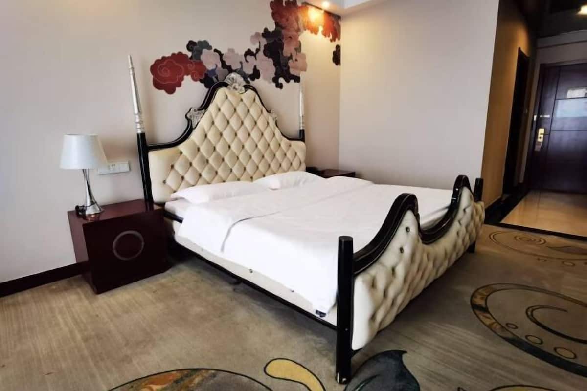 Une chambre d’hôtel comprenant un lit, une table de chevet, une lampe et un élément décoratif mural.
