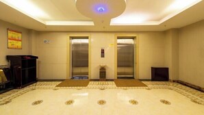 Un vestíbulo amplio con dos ascensores, un mostrador de recepción y un piso con diseño.