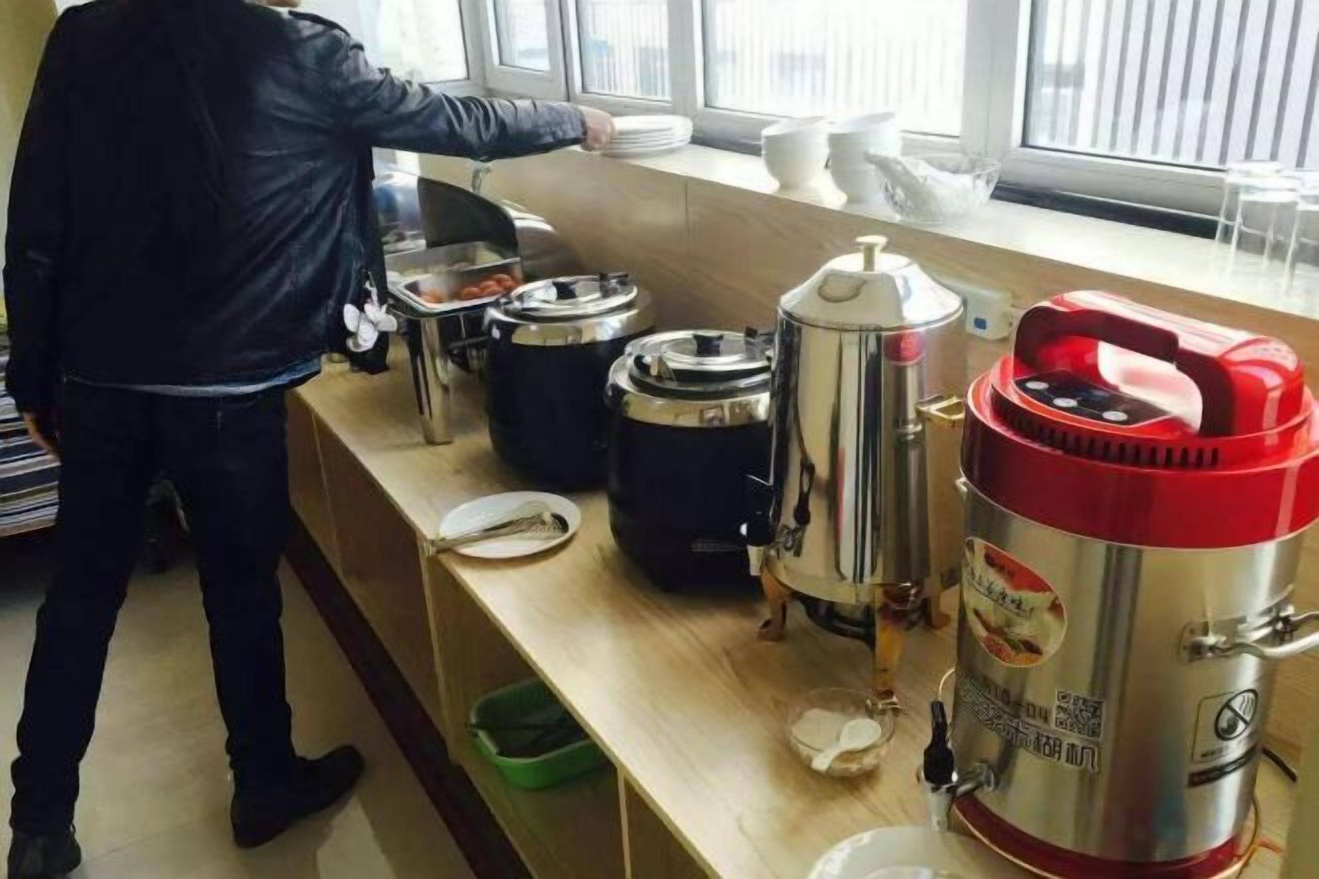 Disposición de bufé con varios recipientes de comida y una persona sirviendo.