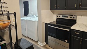 A compact kitchen with a black stove, white appliances, and dark cabinets. - Family-Friendly 4BR Home in Elkton - AC, High-Speed WiFi & Relaxing Vibes (Elkton)