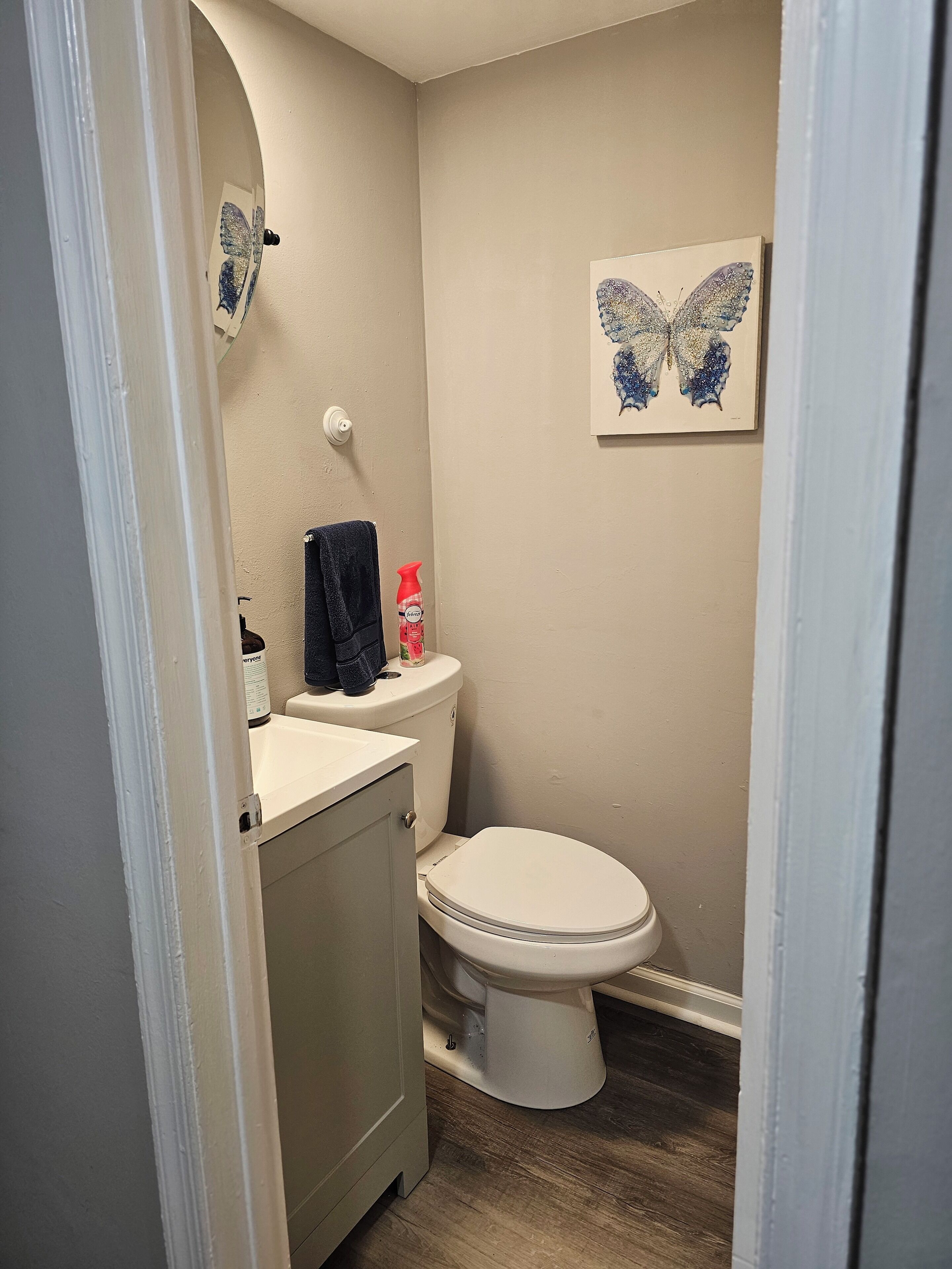 A small bathroom with a toilet, sink, and a towel hanging on the wall.