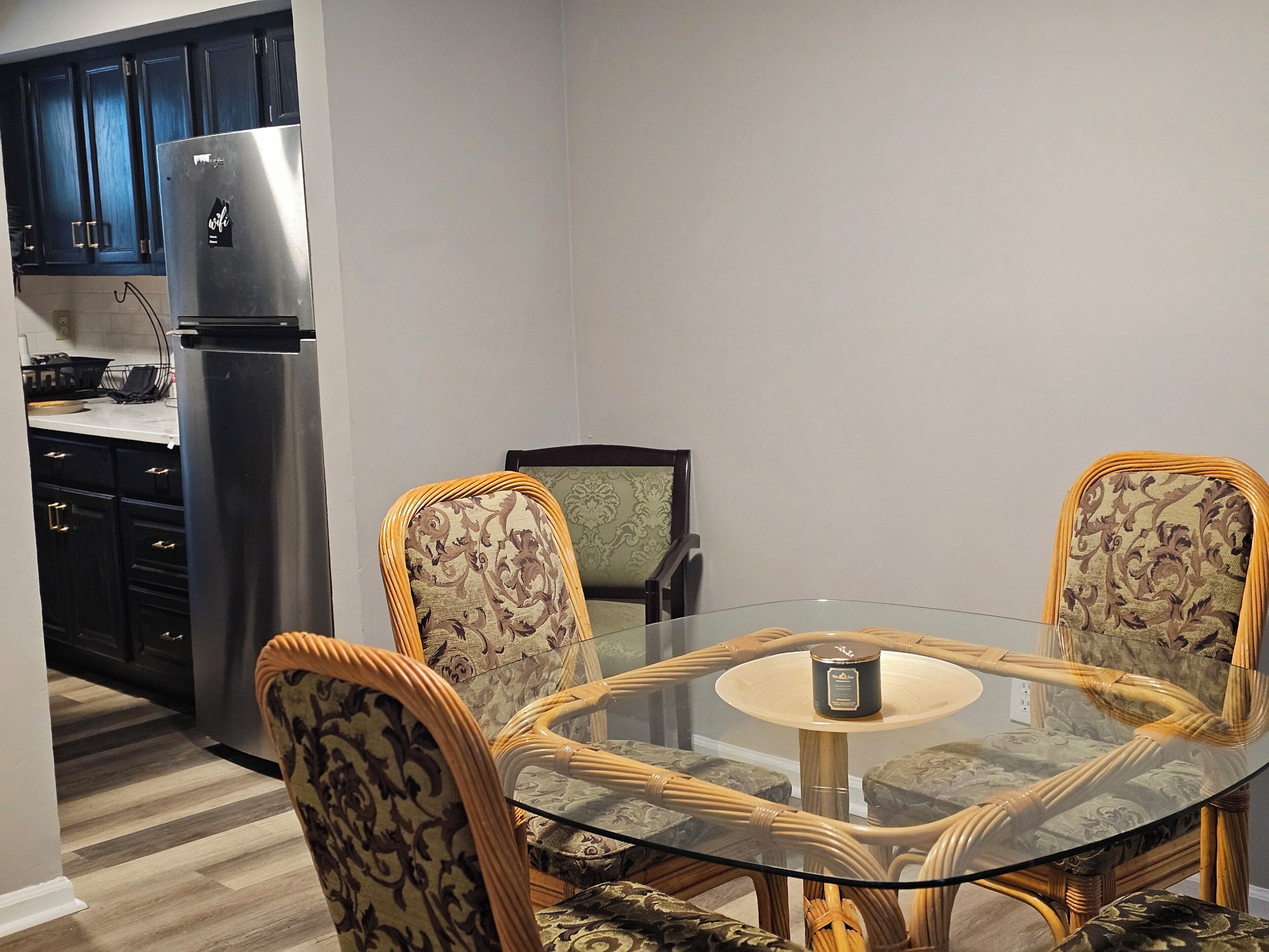 A dining area with a glass table and four chairs with patterned upholstery.