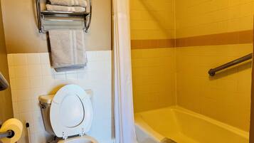 Een badkamer met een toilet, een douche en een handdoekrek met handdoeken.