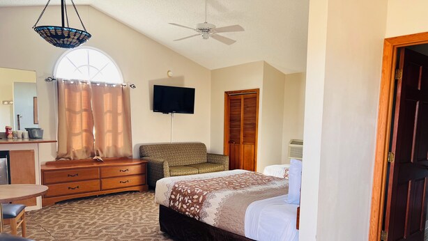 A bedroom with a bed, a desk, a chair, a television, and a wardrobe. - Dew Drop Inn Motel by OYO Miller SD (Miller)
