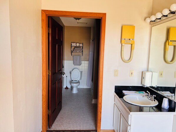 A bathroom with a toilet, sink, and hand dryer.