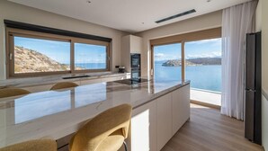 Une cuisine moderne dotée de grandes fenêtres offrant une vue sur un lac et des montagnes.