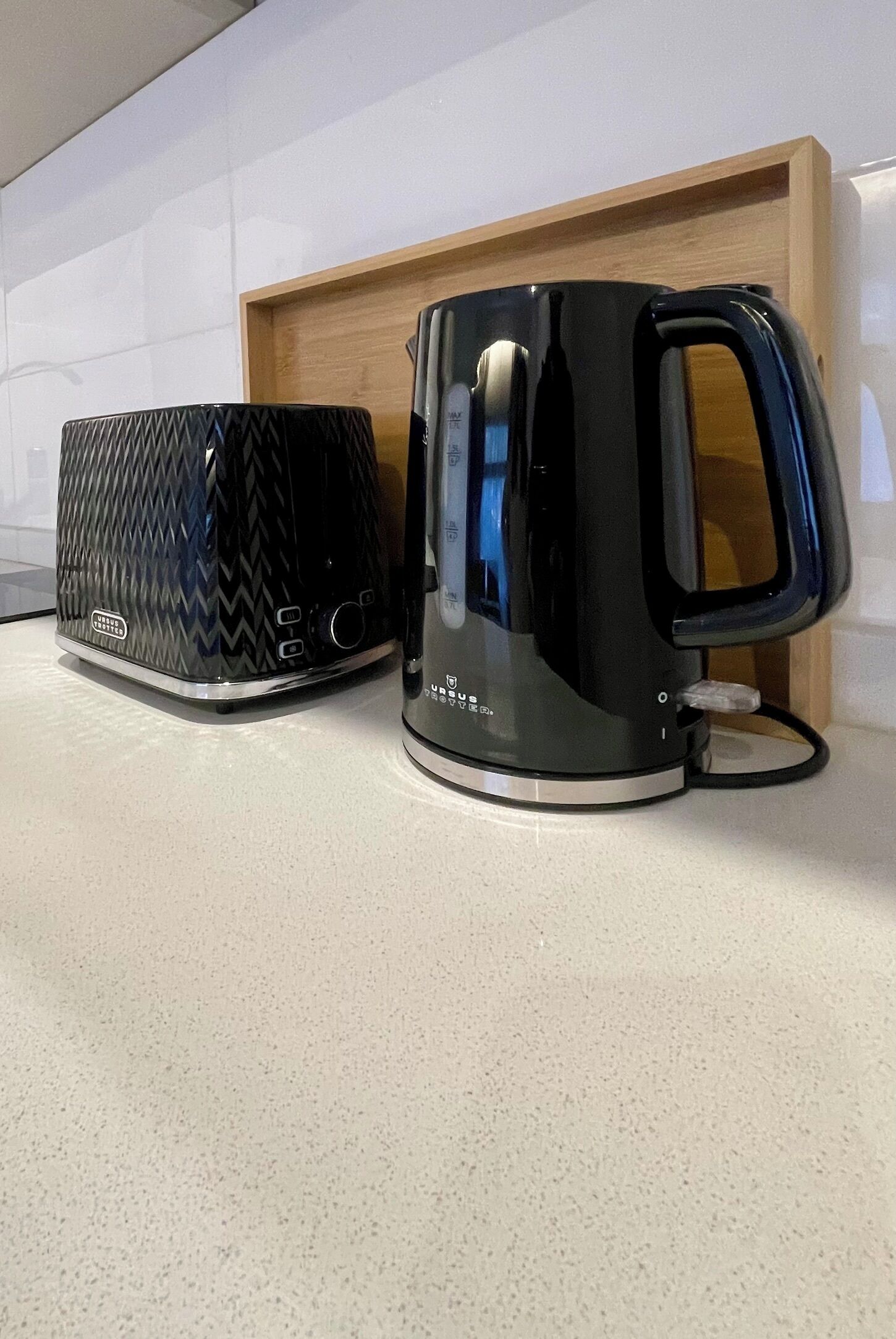 A black kettle and a black mug with a textured pattern on a countertop.
