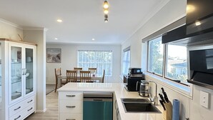 Une cuisine moderne équipée d’un lave-vaisselle, d’une cuisinière et d’un évier. Un coin repas avec une table et des chaises est également disponible.