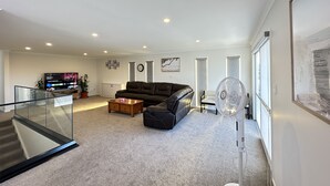 Un salon moderne avec un canapé en cuir, une table basse, un téléviseur et une grande fenêtre.