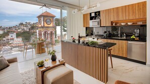 Une cuisine moderne dotée d’un îlot central, de meubles en bois et offrant une vue sur un clocher.