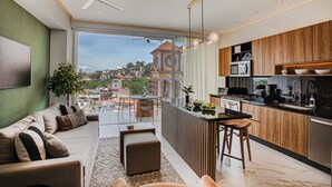 Un appartement moderne doté d’un balcon, d’une cuisine avec des meubles en bois et offrant une vue sur un clocher.