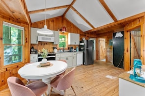 A wooden cabin with a kitchen, dining area, and a large window. - Up Country, Creekside/Hot Tub (Dahlonega)