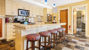 A kitchen with a central island, bar stools, a microwave, and a refrigerator. - Views, King bed, EV charger, 5 min to Downtown (Paso Robles)