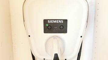 Een Siemens laadstation voor elektrische voertuigen, met een stekker en bedieningspaneel.