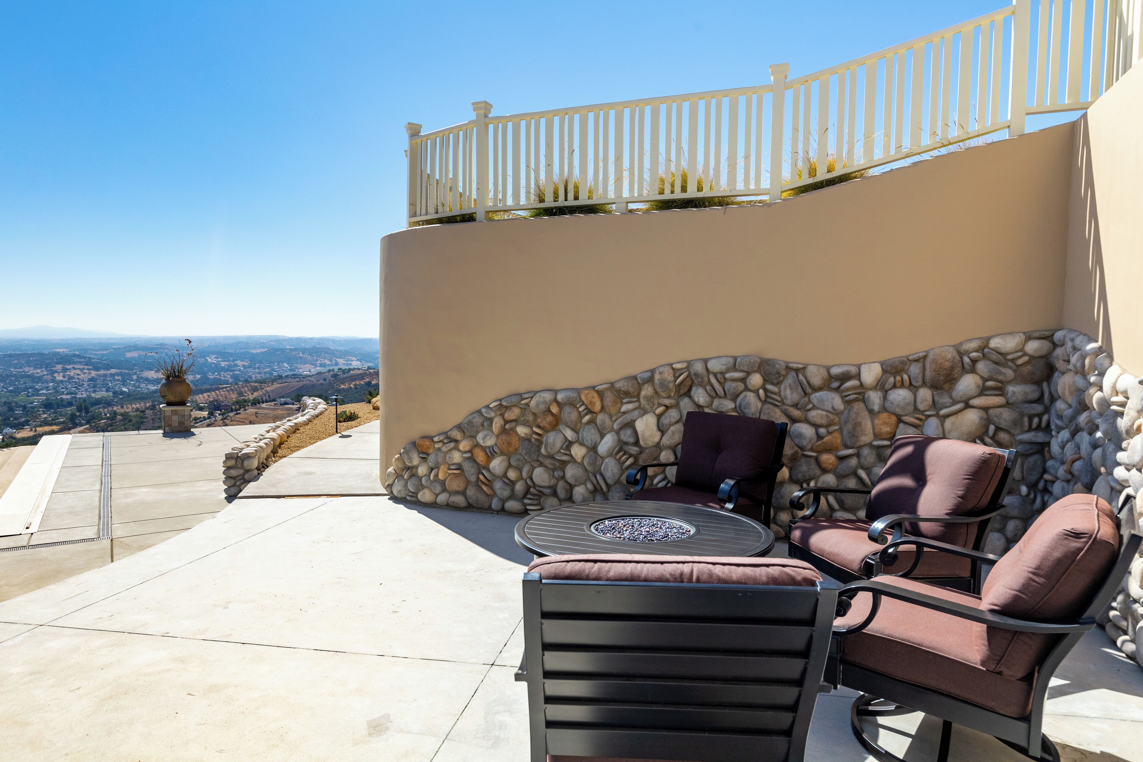 A patio with outdoor furniture, a stone wall, and a view of the landscape.
