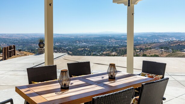 An outdoor patio with a wooden table and wicker chairs, overlooking a scenic landscape. - Views, King bed, EV charger, 5 min to Downtown (Paso Robles)