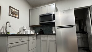 Eine moderne Küche mit grauen Schränken, einem Edelstahlkühlschrank, einer Mikrowelle und einem Spülbecken.