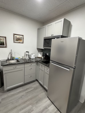 Een moderne keuken met roestvrijstalen apparatuur, grijze keukenkastjes en een marmeren aanrecht.