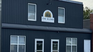 Ein zweistöckiges Gebäude mit einem Schild, auf dem 'The Blend Apartments' steht.