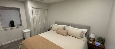 A bedroom with a bed, nightstand, lamp, and a window with blinds.