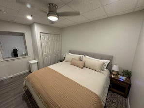 A bedroom with a bed, nightstand, lamp, and a window with blinds.