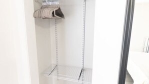 En garderob med hyllor i metall, en klädstång och ett grått heltäckningsmatta på golvet.