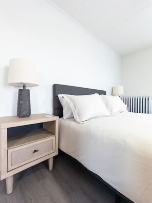 Quarto com uma cama, duas mesas de cabeceira e um radiador.