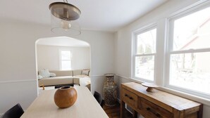 Una cocina moderna con una mesa de madera, un jarrón y un armario de madera cerca de una ventana.
