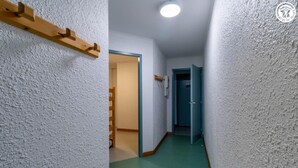 A narrow hallway with white textured walls, a green carpet, and a wooden handrail on the left.